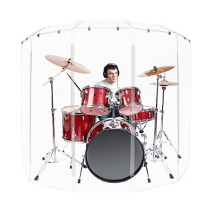 May include: A red drum set with a clear acrylic soundproof barrier. The drummer is wearing headphones and is playing the drums.