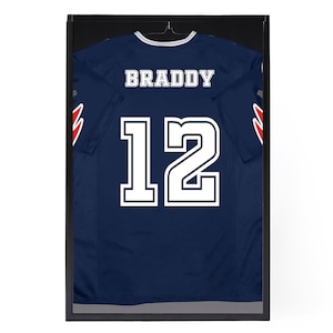 May include: A navy blue jersey with white lettering and the number 12. The name "BRADDY" is on the back of the jersey.