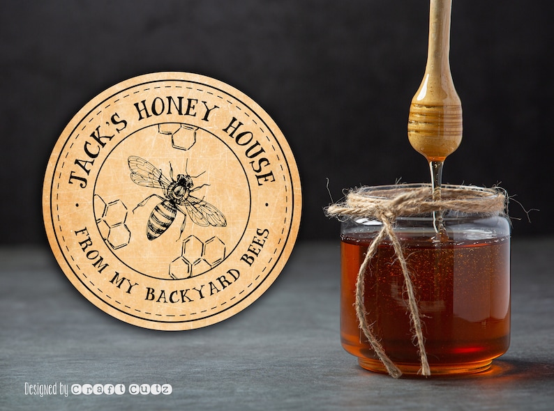 Peut inclure: Une &eacute;tiquette ronde brune avec le texte "Jack's Honey House From My Backyard Bees" en lettres noires. Une illustration en noir et blanc d'une abeille avec du miel est au centre de l'&eacute;tiquette. Un pot de miel avec un n&oelig;ud en ficelle est en arri&egrave;re-plan.