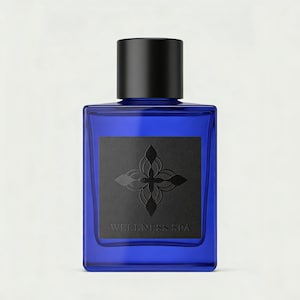 May include: A rectangular cobalt blue glass bottle with a matte black cylindrical cap. A square black label on the front features a dark embossed floral emblem above the text WELLNESS SPA in a simple serif font, centered on the glass surface.