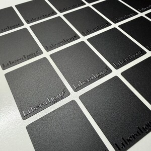 May include: A grid of rectangular black cards with a textured matte finish. Each card features the embossed text Liberation scent co in a stylized font. The cards are arranged in a repeating pattern, showcasing the consistent branding and design.