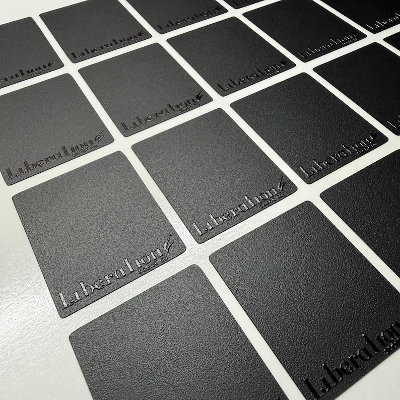 May include: A grid of rectangular black cards with a textured matte finish. Each card features the embossed text Liberation scent co in a stylized font. The cards are arranged in a repeating pattern, showcasing the consistent branding and design.