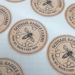 Peut inclure: Cinq &eacute;tiquettes rondes en papier brun avec du texte noir et une illustration d'abeille. Le texte sur les &eacute;tiquettes indique "Schnagl Gaggle Farms" et "From My Backyard Bees".