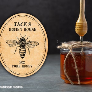 Peut inclure: Une &eacute;tiquette ronde brune avec une illustration d'abeille et le texte "Jack's Honey House 100% Pure Honey"  Con&ccedil;u par Craft Quiz.