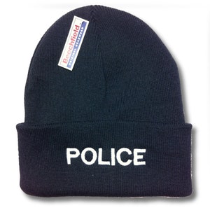 May include: A navy blue knitted beanie with a white "POLICE" embroidered on the front. The beanie has a white label that reads "Beechfield Original Headwear" on the side.