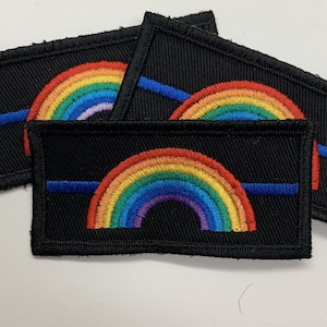 May include: Three black embroidered patches featuring a rainbow and a thin blue line. The patches are made from black fabric with a white outline.
