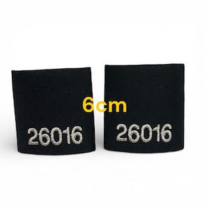 May include: Two black fabric patches, each with the embroidered number "26016" in silver thread. The patches are approximately 6 cm wide. The text "6cm" is in yellow.