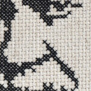 May include: Black and white cross-stitch embroidery on a beige fabric background. The design features a stylised floral pattern.