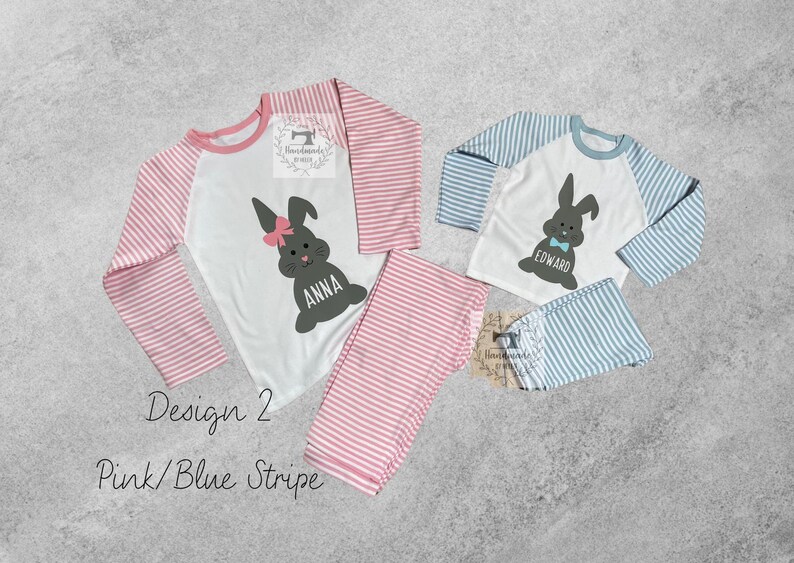 May include: Two children's pajamas with a pink and blue stripe design. The pajamas feature a white top with a bunny rabbit graphic and the names "Anna" and "Edward".