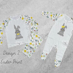 May include: Two white pajamas with an Easter bunny design. One pajama set has a long-sleeved shirt with a bunny and the name "Henry" printed on it. The other pajama set is a one-piece with a bunny and the name "Poppy" printed on it.