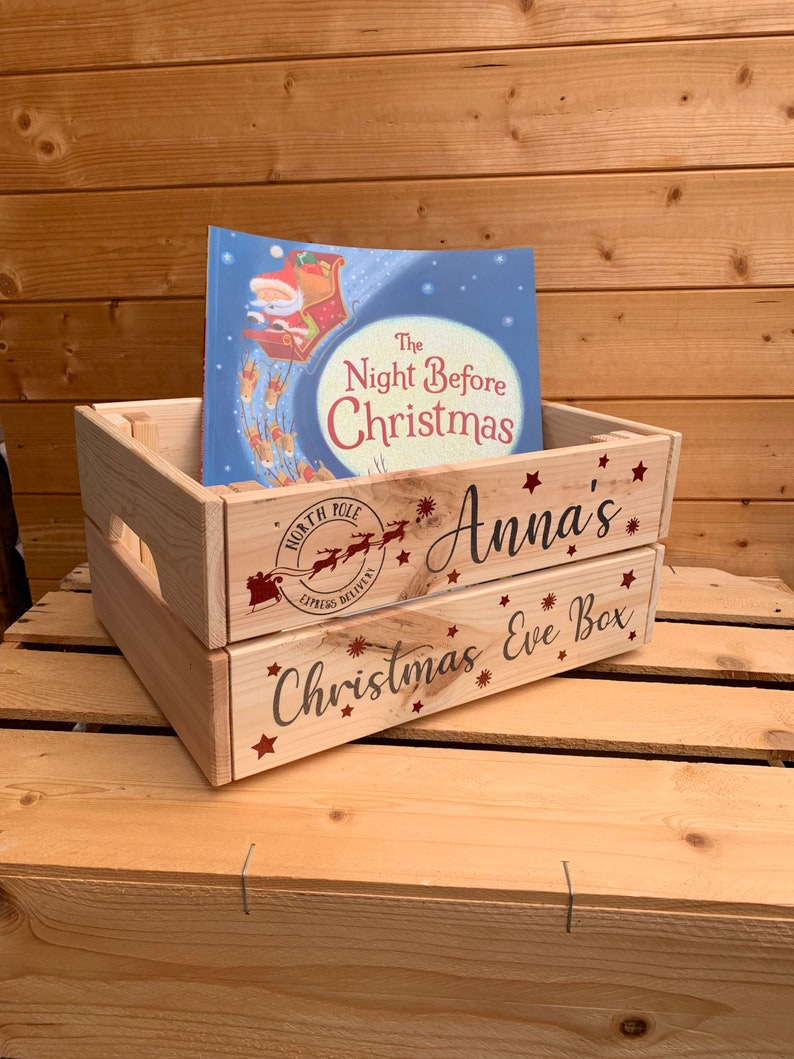 May include: A wooden Christmas Eve box with a red and white North Pole Express Delivery stamp, the words "Anna's Christmas Eve Box" and a copy of the book "The Night Before Christmas".
