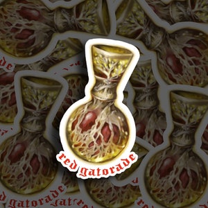 May include: A sticker featuring a golden bottle with a red liquid inside. The bottle is surrounded by a network of red veins and the text "red gatorade" is written in red on the bottom.