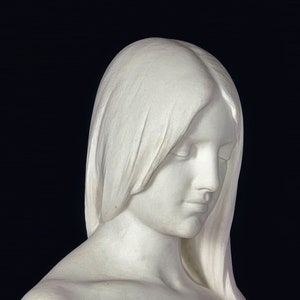 May include: A white marble sculpture of a woman with her head bowed and eyes closed. Her hair is long and flowing, and she is wearing a simple, elegant dress.