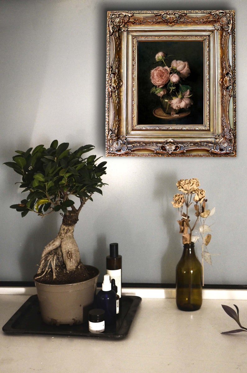 Może przedstawiać: Namalowany obraz r&oacute;żowych piwonii w wazonie na stole. Obraz jest w złotej ramie z ozdobnymi detalami. Na stole stoi bonsai w doniczce z butelkami płynu i małym słoikiem.