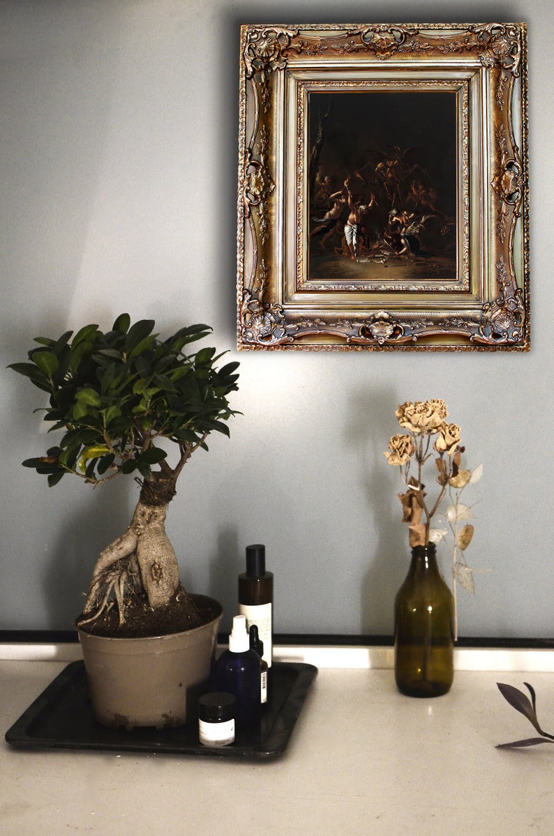 Pode incluir: Uma pintura ornamentada com moldura dourada est&aacute; pendurada numa parede cinzenta. Uma &aacute;rvore bonsai num vaso castanho, uma bandeja preta com garrafas e um vaso com flores secas est&atilde;o numa superf&iacute;cie branca. A pintura retrata uma cena escura com figuras.