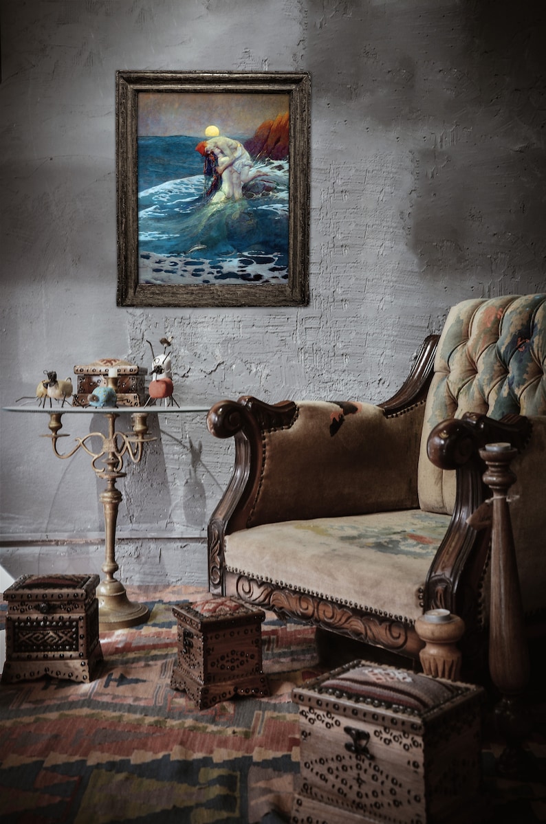May include: A vintage-style, brown leather armchair with a floral patterned upholstery. The armchair is in a room with a framed painting of a mermaid and a table with decorative boxes.