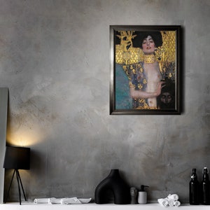 May include: A framed painting of a woman with long dark hair wearing a gold and blue patterned robe. The woman is looking to the left and has a serious expression. The painting is set against a gray wall.