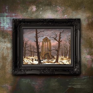 May include: A framed painting depicting a gothic ruin in a winter landscape. The artwork features leafless trees, a snow-covered ground, and a group of figures. The frame is black with ornate detailing.