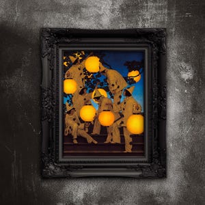 May include: A framed print featuring a vintage illustration of figures in white costumes holding glowing lanterns. The artwork is set against a blue and yellow backdrop, framed in a black ornate frame, and mounted on a textured gray wall.