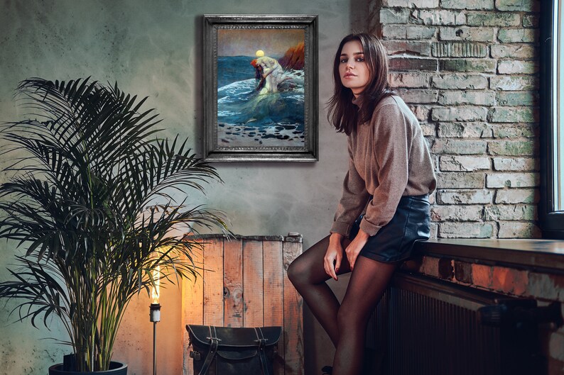 May include: A woman wearing a brown jumper and black shorts sits on a windowsill in front of a brick wall. A framed painting of a mermaid in the ocean hangs on the wall behind her.