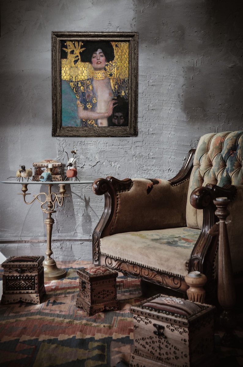 May include: A framed painting of a woman with long dark hair wearing a gold and blue robe. The painting is hanging on a gray brick wall above a brown velvet sofa. There are several small wooden boxes on a table in front of the sofa.