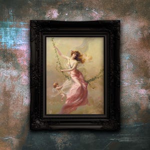 May include: A framed wall art print featuring a painting of a woman in a flowing pink dress on a vine swing, accompanied by a small winged figure. The artwork is enclosed in an ornate, dark black rectangular frame with detailed carvings.