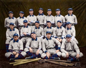 Peut inclure: Une photo d'équipe de baseball vintage avec 16 joueurs en uniforme blanc avec des garnitures bleues et des casquettes assorties. Les joueurs sont disposés en trois rangées, la rangée du devant étant assise et les deux rangées du derrière debout. Les joueurs sourient tous et regardent la caméra. L'équipe tient des bâtons de baseball et un gant.