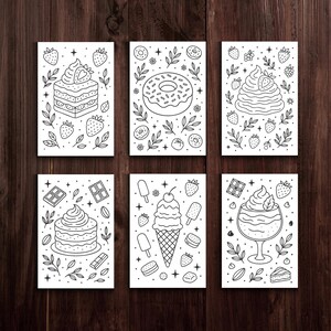 May include: Six black and white dessert-themed art prints. Each print features a different dessert, including a layered cake, donut, ice cream cone, and parfait. The illustrations are surrounded by decorative elements like strawberries and leaves.
