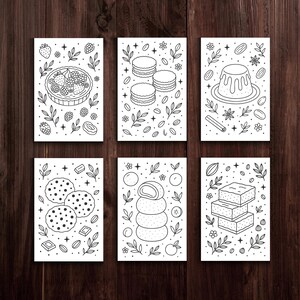 May include: Six black and white illustrated cards featuring various desserts. The cards depict a fruit tart, macarons, a flan, chocolate chip cookies, mochi, and layered brownies, all surrounded by decorative elements.