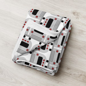 May include: A white fleece blanket with a repeating pattern of gray and black ovens with red knobs.