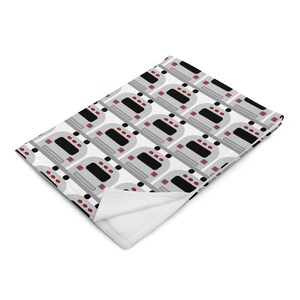 May include: A white fleece blanket with a repeating pattern of gray and black subway cars with red lights.