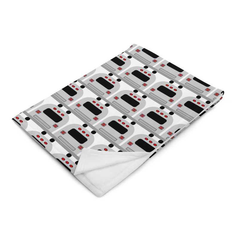 May include: A white fleece blanket with a repeating pattern of gray and black subway cars with red lights.