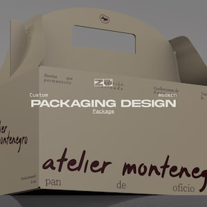 Op de afbeelding: Een beige kartonnen doos met een handvat, voorzien van de tekst "atelier montenegro pan de oficio" in donkerbruin, samen met "Custom PACKAGING DESIGN" en "Recetas que permanecen" gedrukt in wit en donkerbruin op de voorzijde.