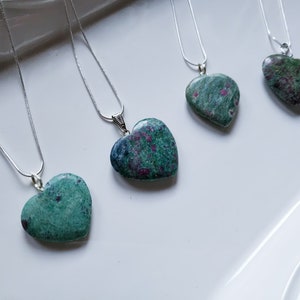 May include: Five silver necklaces with heart-shaped green and pink ruby zoisite pendants. The pendants have a mottled, marbled appearance.