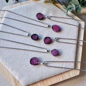 May include: Five silver necklaces with pink and purple gemstone pendants. The pendants are all different shapes and sizes, and they are all set in silver.