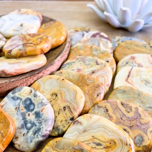 May include: A collection of polished agate stones in various shades of yellow, brown, and white. The stones are smooth and have a natural, organic pattern.