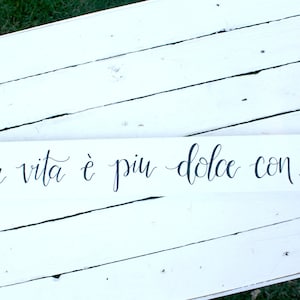 May include: White wooden sign with black calligraphy that reads "La vita è piu dolce con te."