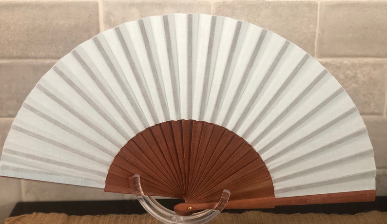May include: A white hand fan with a brown wooden handle. The fan is open and the wooden handle is visible.