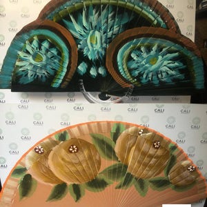 Puede incluir: Dos abanicos de mano con dise&ntilde;os pintados. El abanico superior tiene un dise&ntilde;o abstracto azul y verde con el texto "Abstract Kiwi". El abanico inferior tiene un fondo melocot&oacute;n con tres kiwis amarillos y hojas verdes.