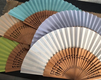 May include: Five hand fans with wooden frames and different colored fabric panels. The fans are arranged in a semi-circle, with the largest fan in the center.