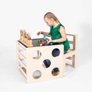 Young girl drawing with colorful pencils at a natural birch plywood convertible cube table in studio.