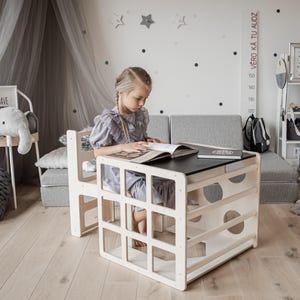 A child focused on reading a book at a natural wood color cube desk in a cozy playroom.