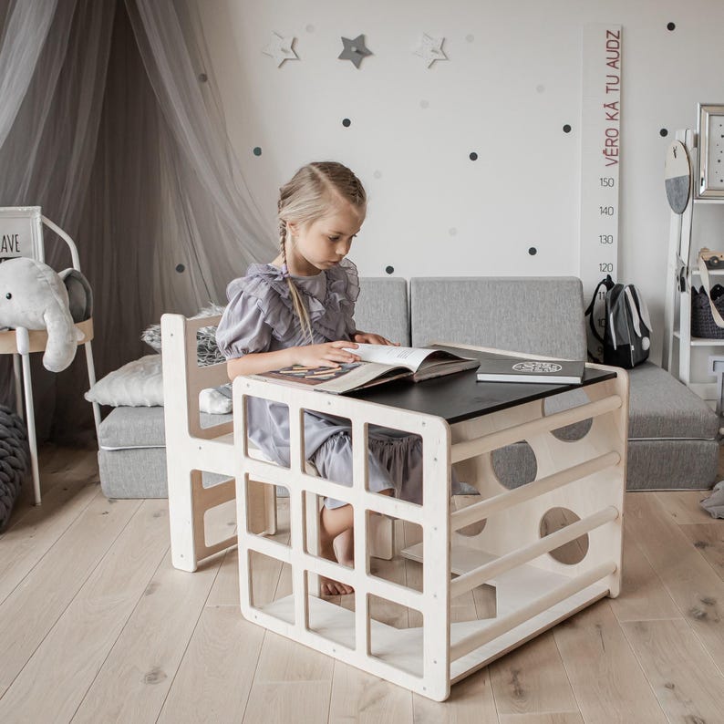 A child focused on reading a book at a natural wood color cube desk in a cozy playroom.