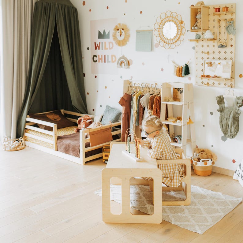 Light birch toddler furniture arranged in a Scandinavian inspired nursery with a floor canopy.