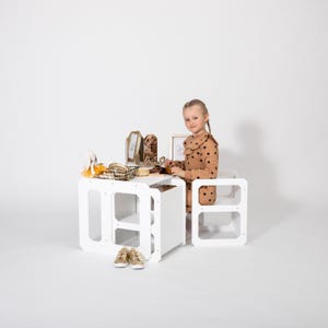 Girl playing with toys at a white convertible toddler table with nested chairs in studio.