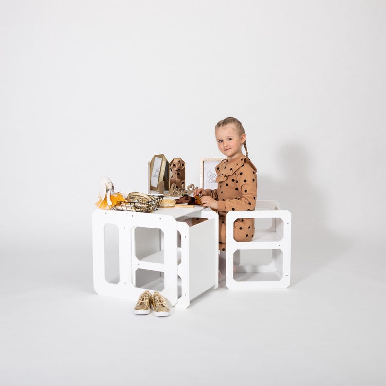 Girl playing with toys at a white convertible toddler table with nested chairs in studio.