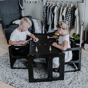 Two children drawing together at a black convertible toddler table set.