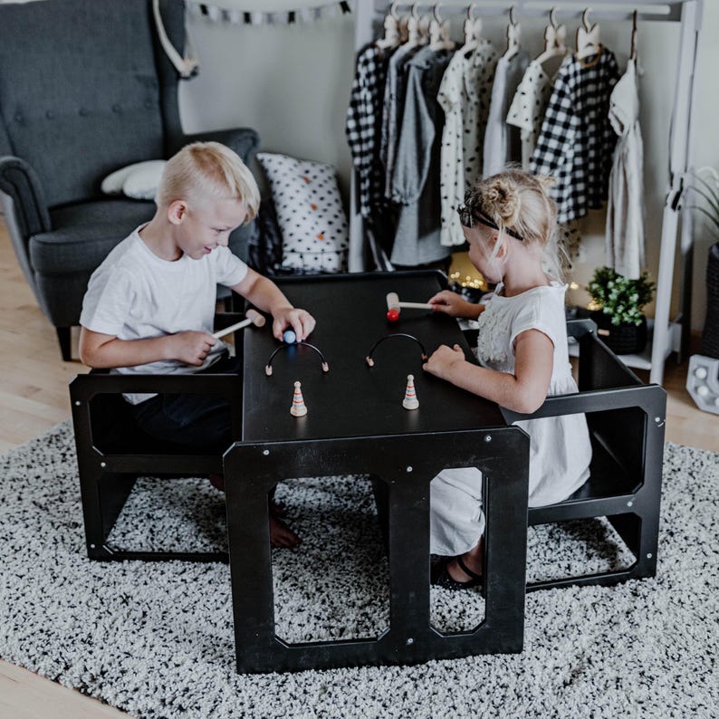 Two children drawing together at a black convertible toddler table set.