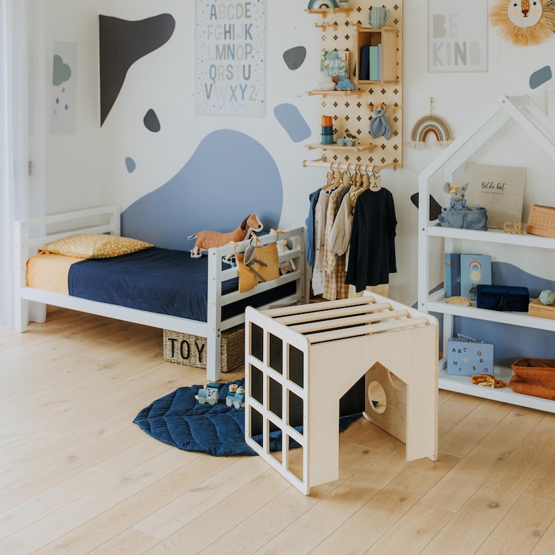 Convertible play cube placed near a bed frame, acting as an indoor climbing structure.