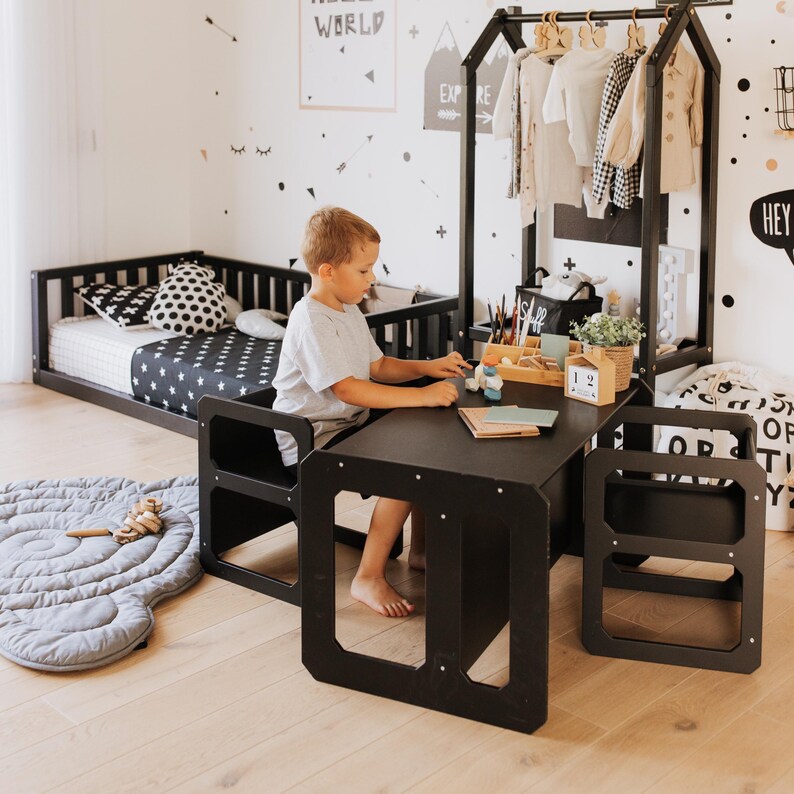 Boy sitting at a black toddler activity desk in a modern black and white kids bedroom.